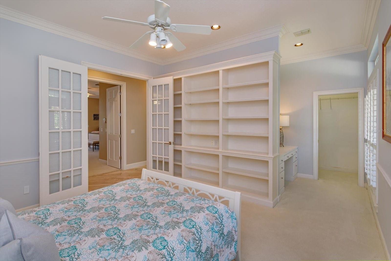 bedroom with white built in shelves and white desk